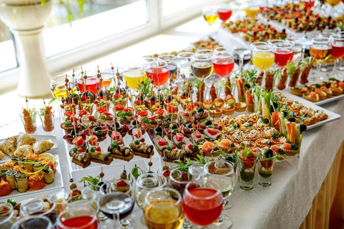 A buffet table filled with lots of food and wine glasses