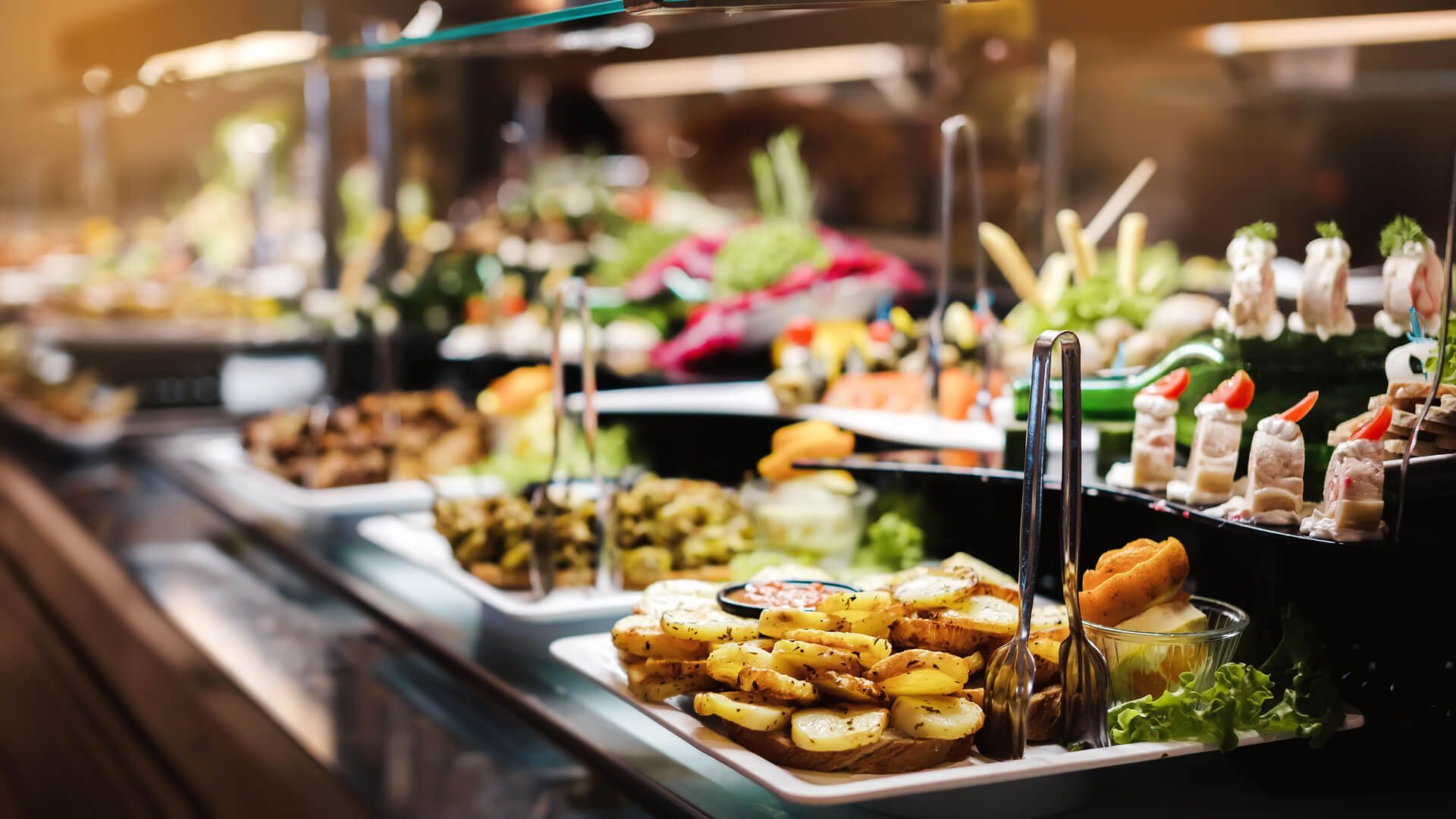 A buffet line filled with lots of food and tongs