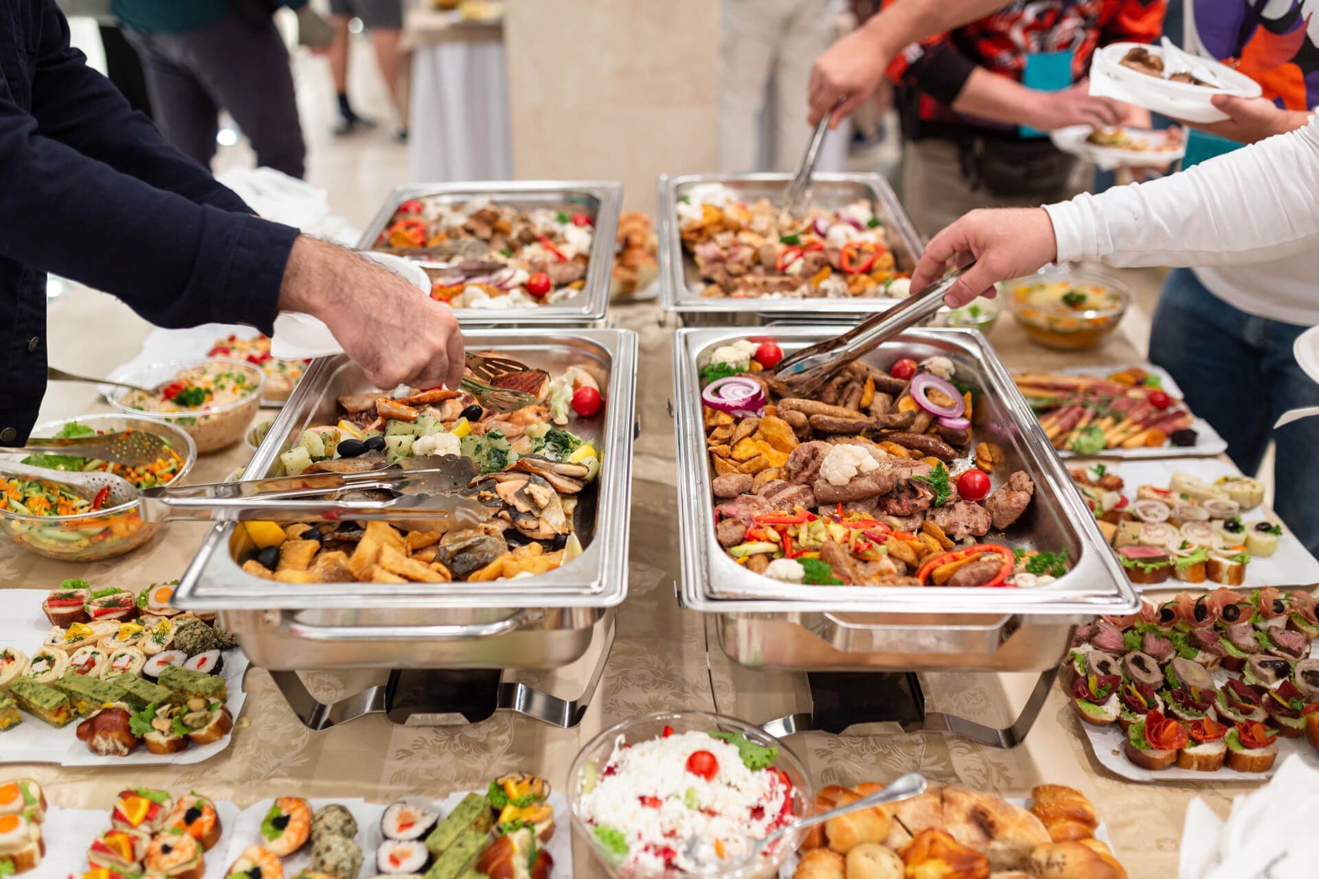A group of people are taking food from a buffet table