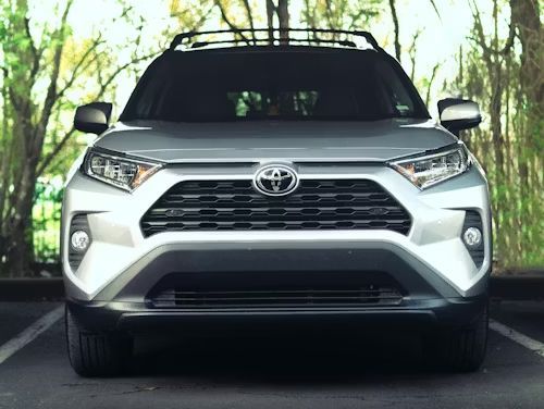 Silver Toyota RAV4 SUV, front view. Parked against a backdrop of trees.