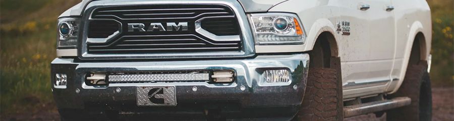A white ram truck is parked on a dirt road.