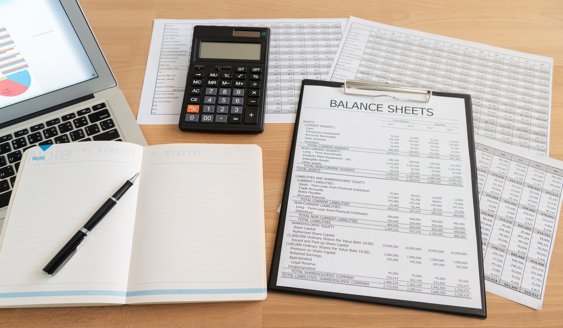 Man in glasses reviews documents with another person at a table, orange pen pointing.