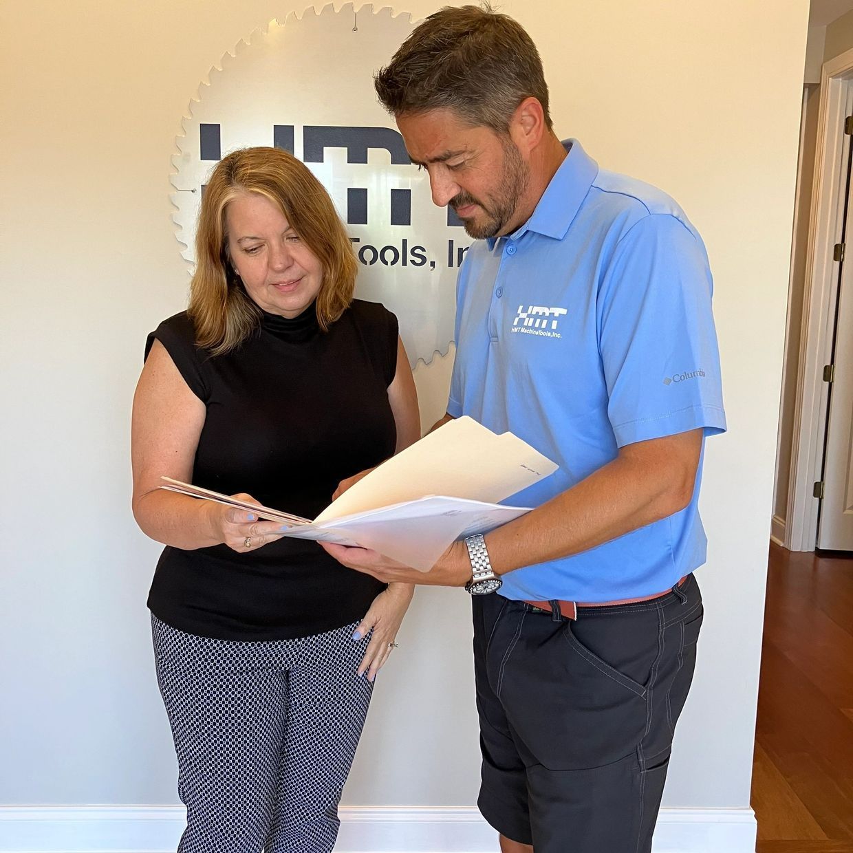 Person writing a check, using a calculator and laptop on a desk.