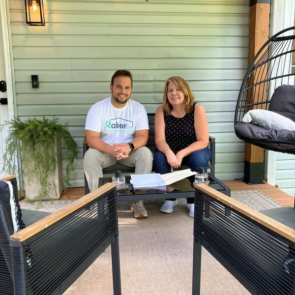 Man in glasses reviews documents with another person at a table, orange pen pointing.