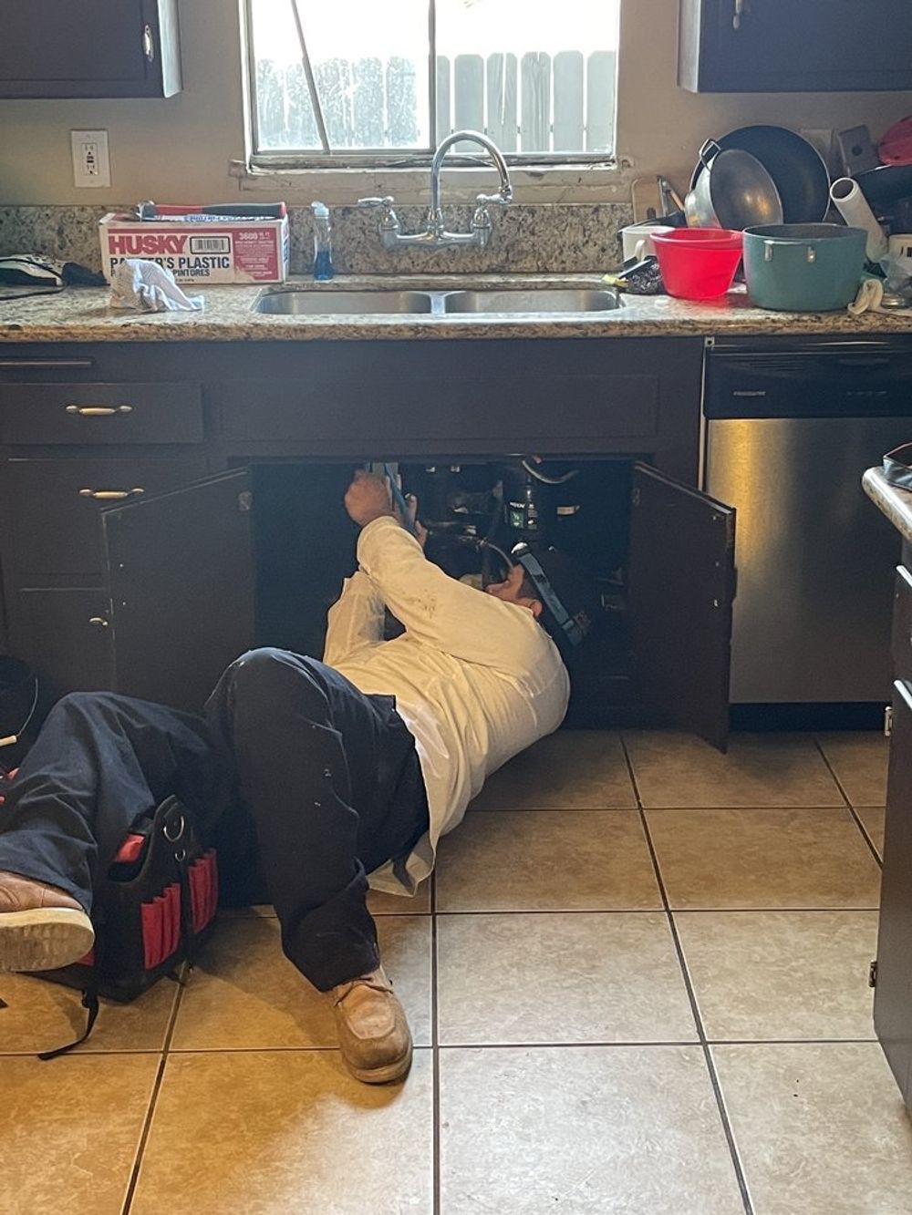 Excavated hole with purple hose, silver machine, and person working. Yellow caution tape.