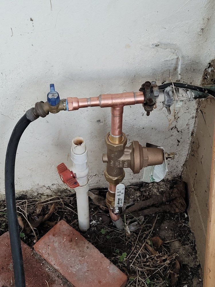 Copper water pipes with a regulator and valve are attached to a garden hose.