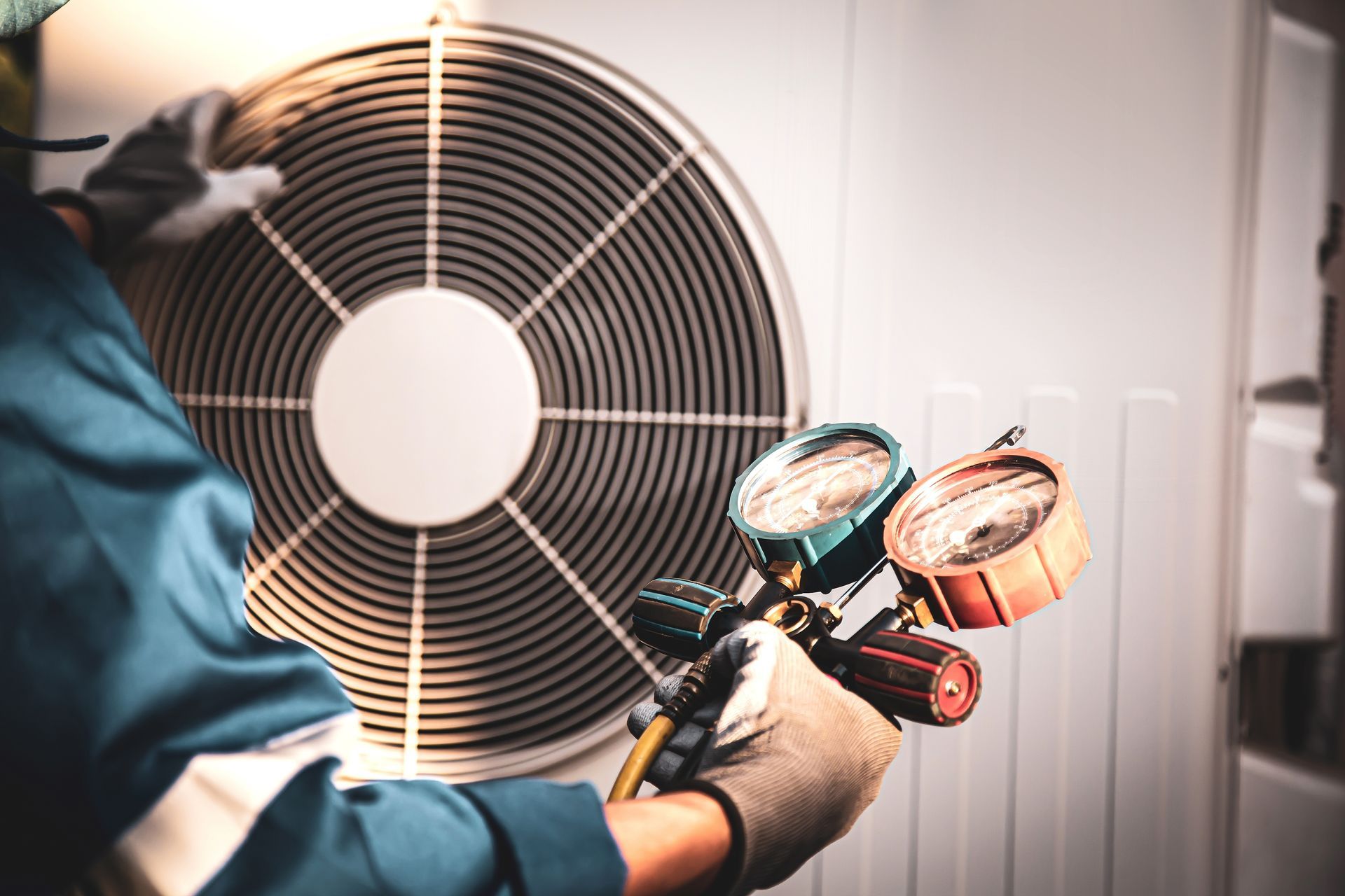 Technician using gauges to service a large HVAC unit with a circular fan indoors