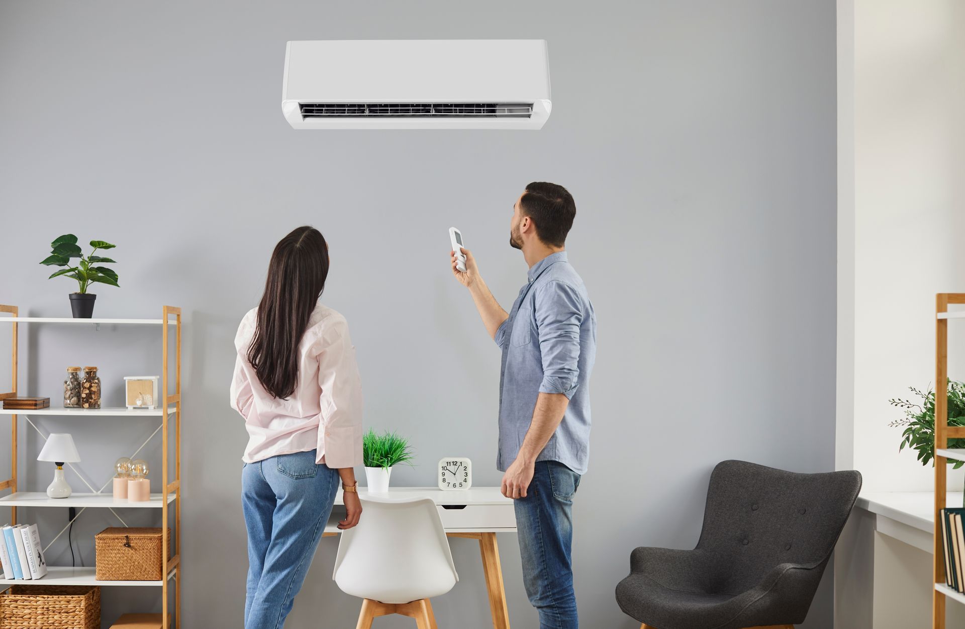 Two people using a smartphone to control a wall-mounted air conditioner in a modern living room.