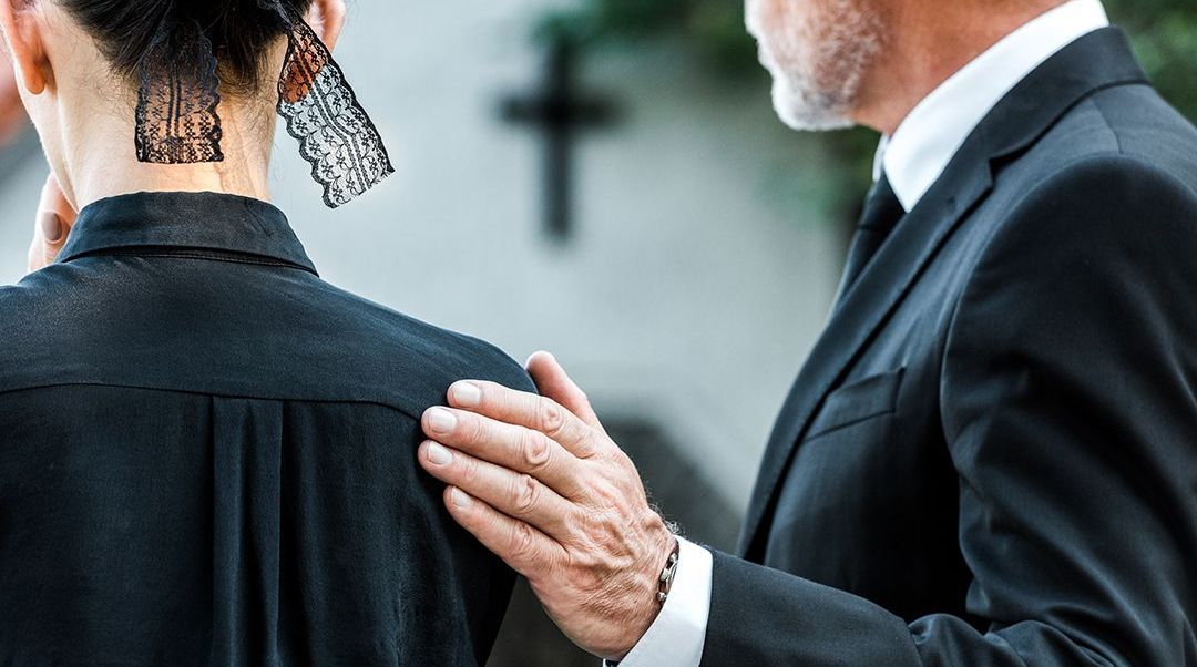 a man in a suit is comforting a woman at a funeral .
