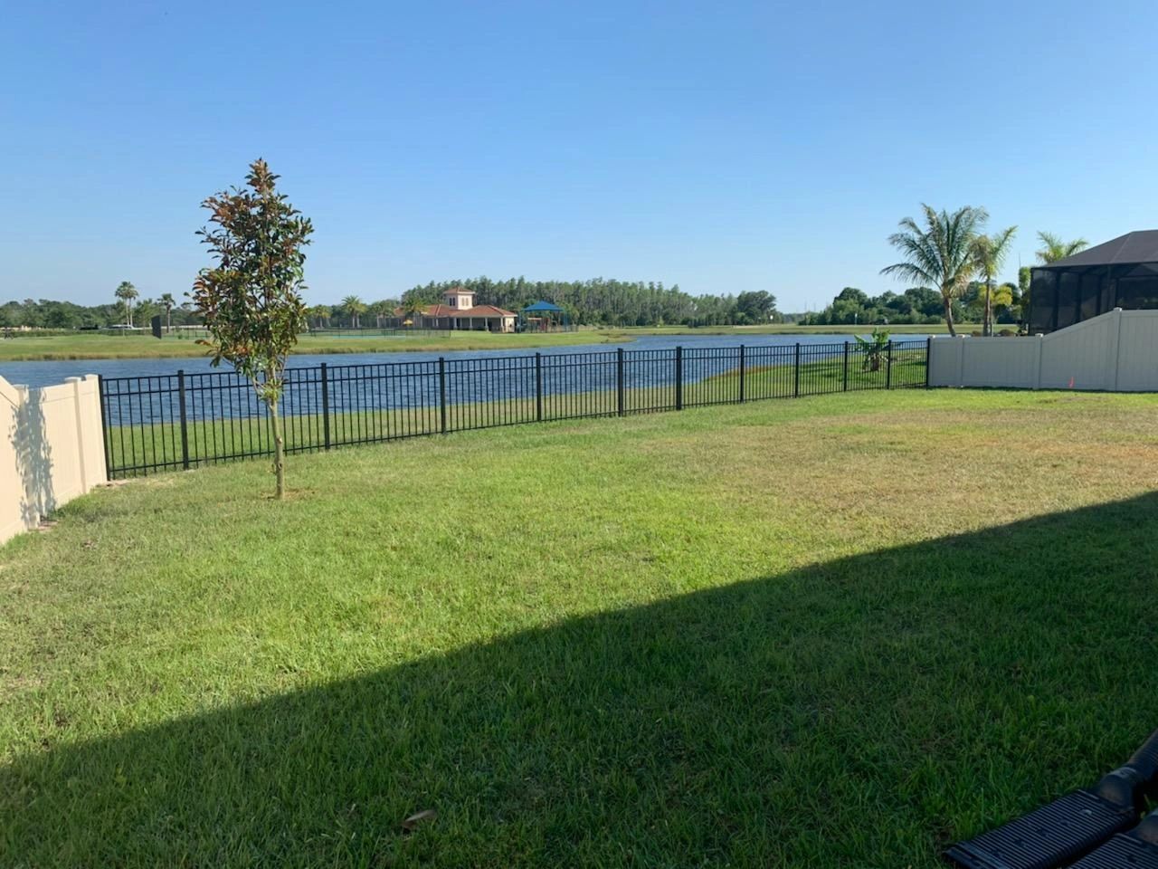 A fence surrounds a lush green field with a lake in the background.