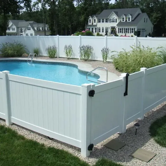 A white fence surrounds a large swimming pool