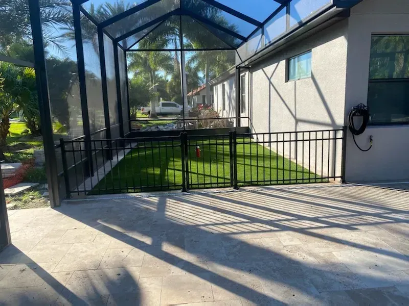 A house with a screened in porch and a fence in front of it.