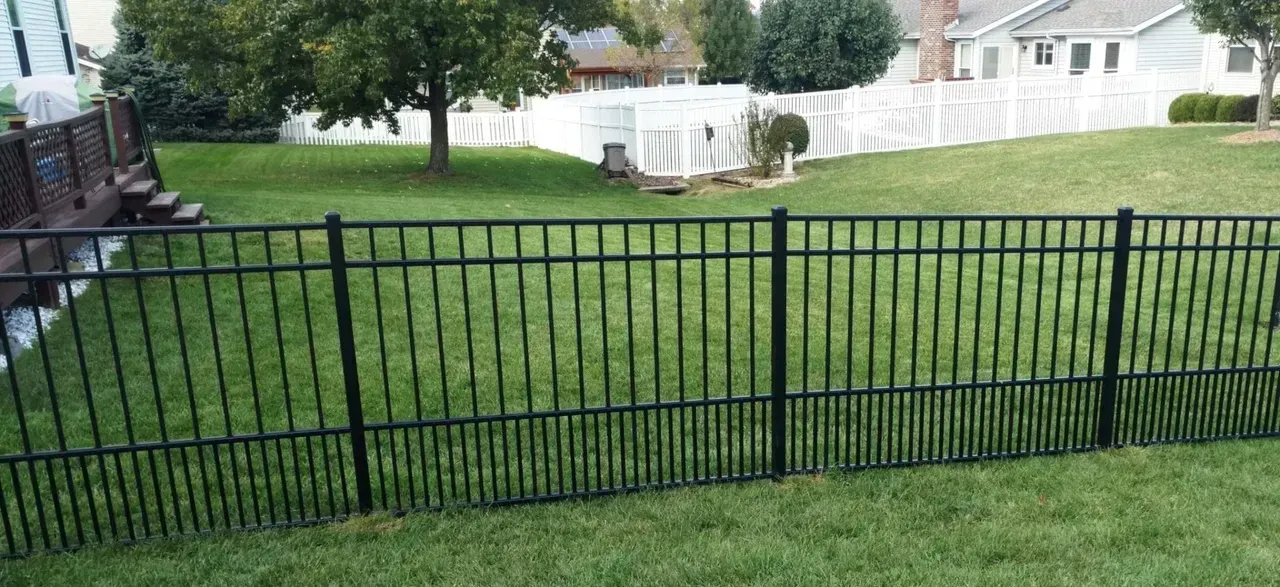 A black fence surrounds a lush green yard.