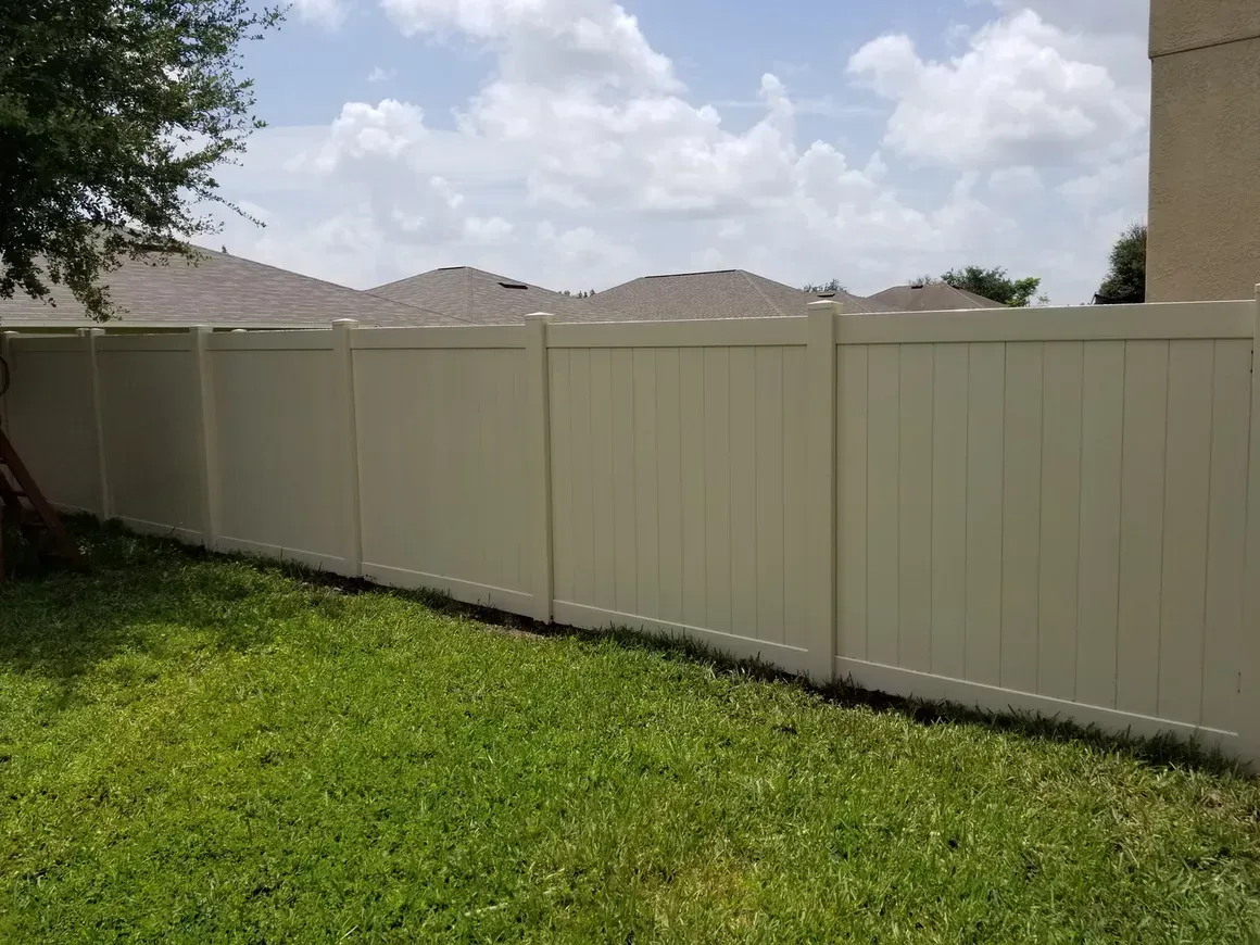 A white fence surrounds a lush green lawn in a backyard.
