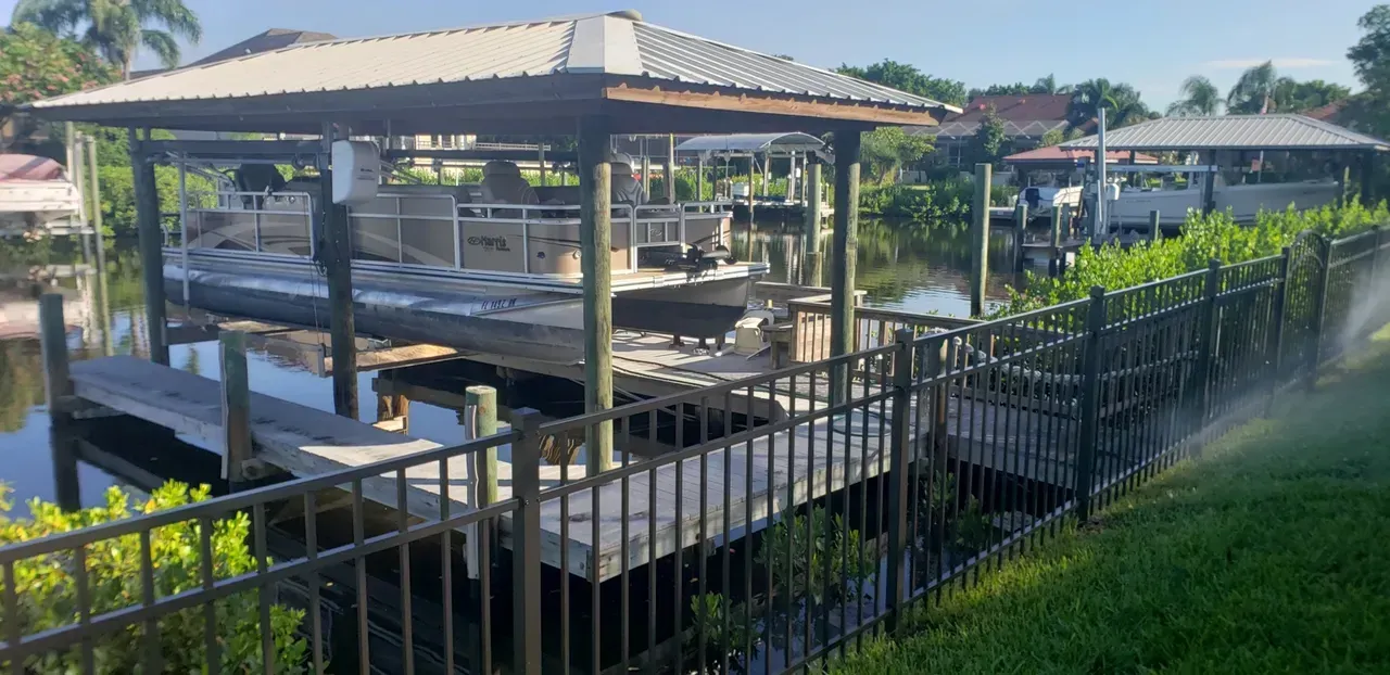 A dock with a gazebo overlooking a body of water next to a fence.