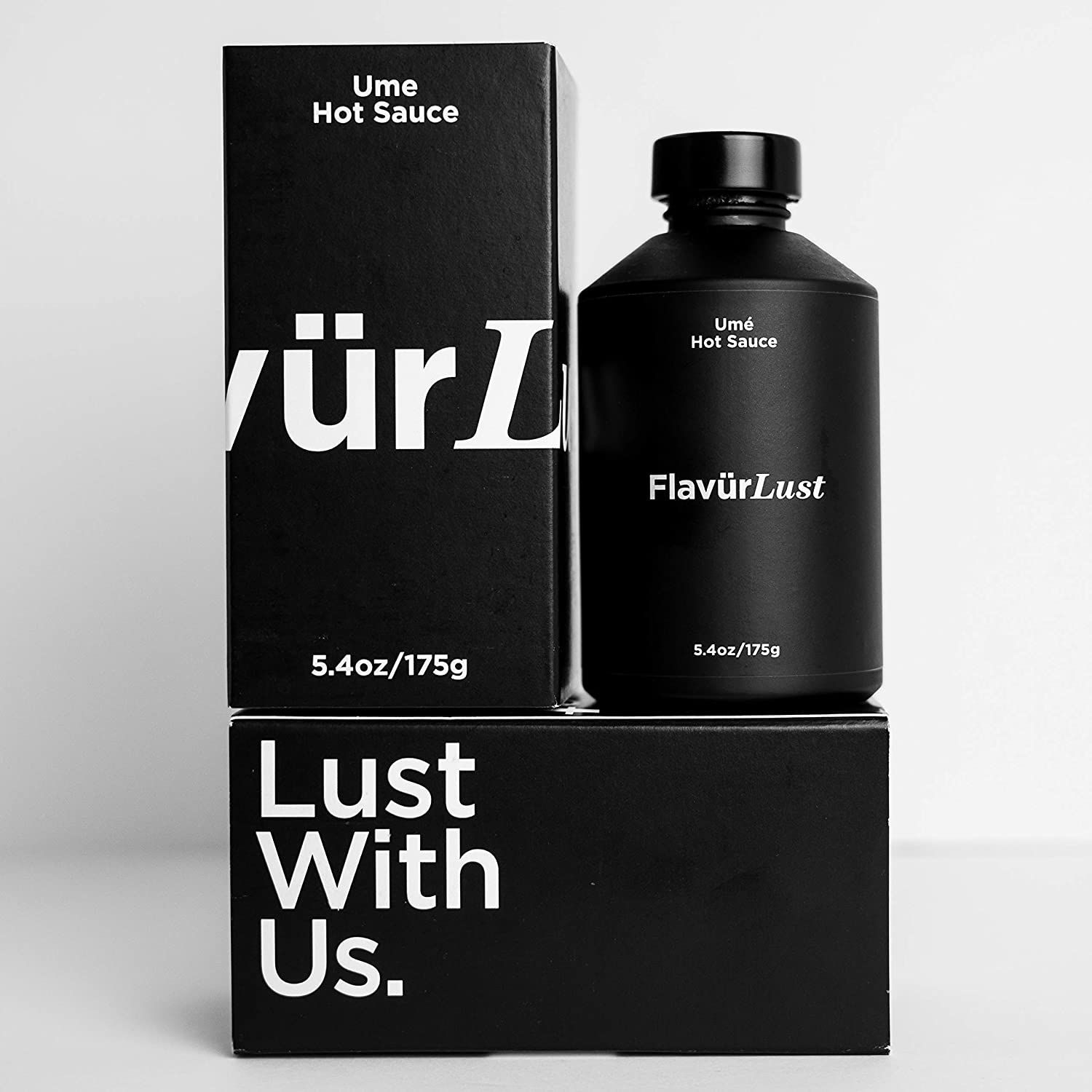 A bottle of hot sauce next to a box that says lust with us