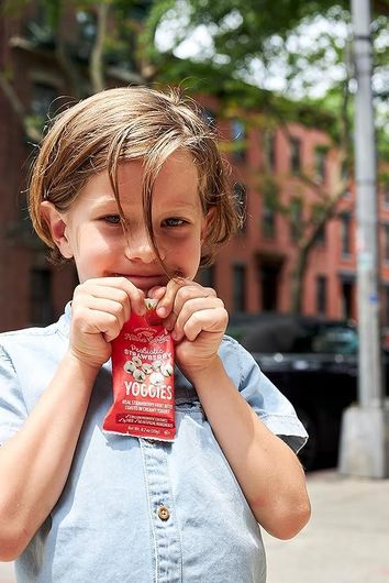 A young boy is eating a candy bar that says ' strawberry ' on it