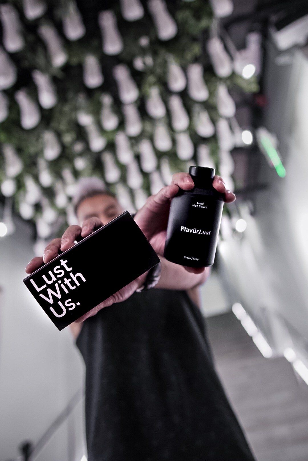 A person holding the packing of flavurlust hot sauce bottle