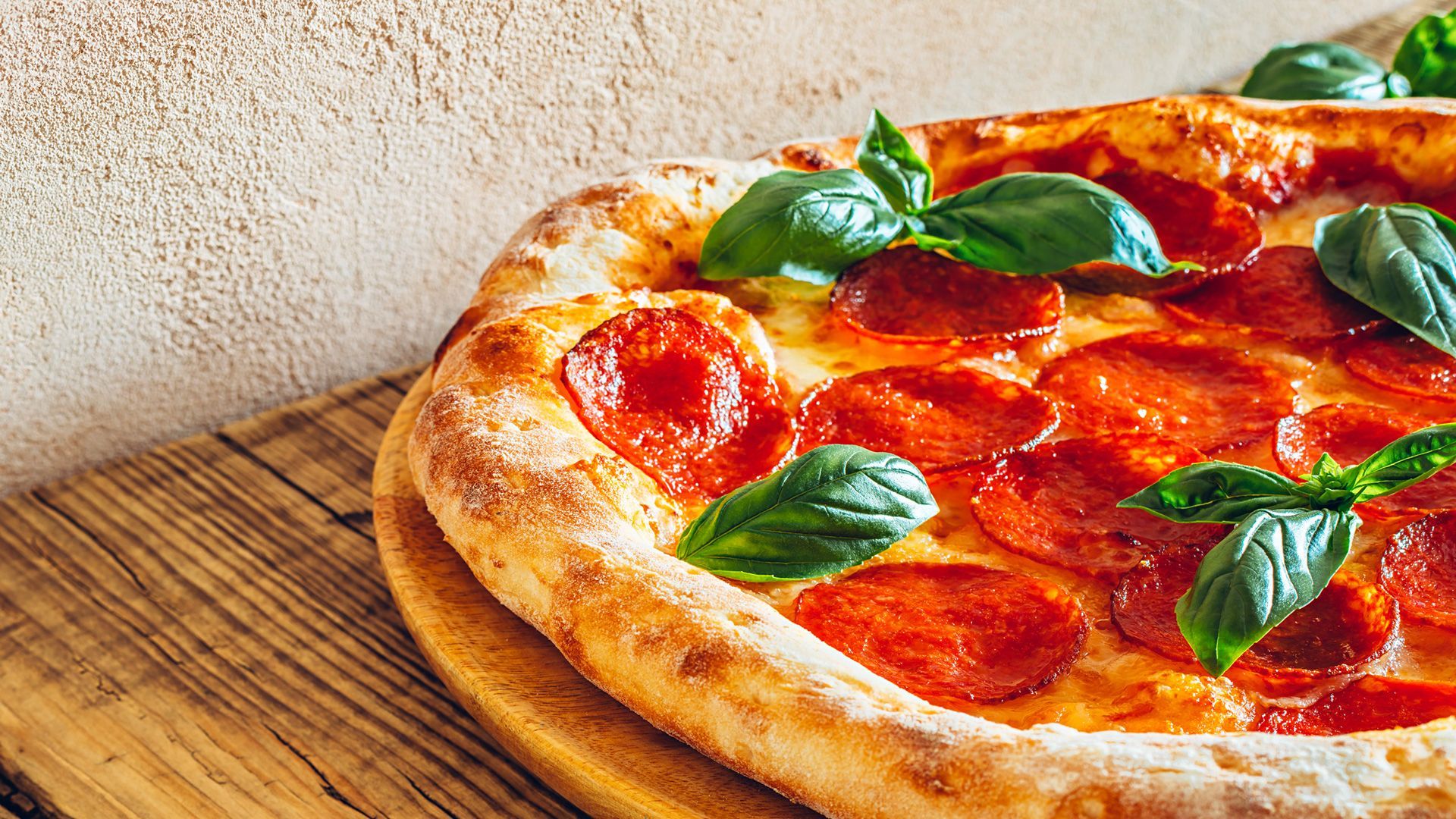 A pepperoni pizza is sitting on a wooden cutting board.