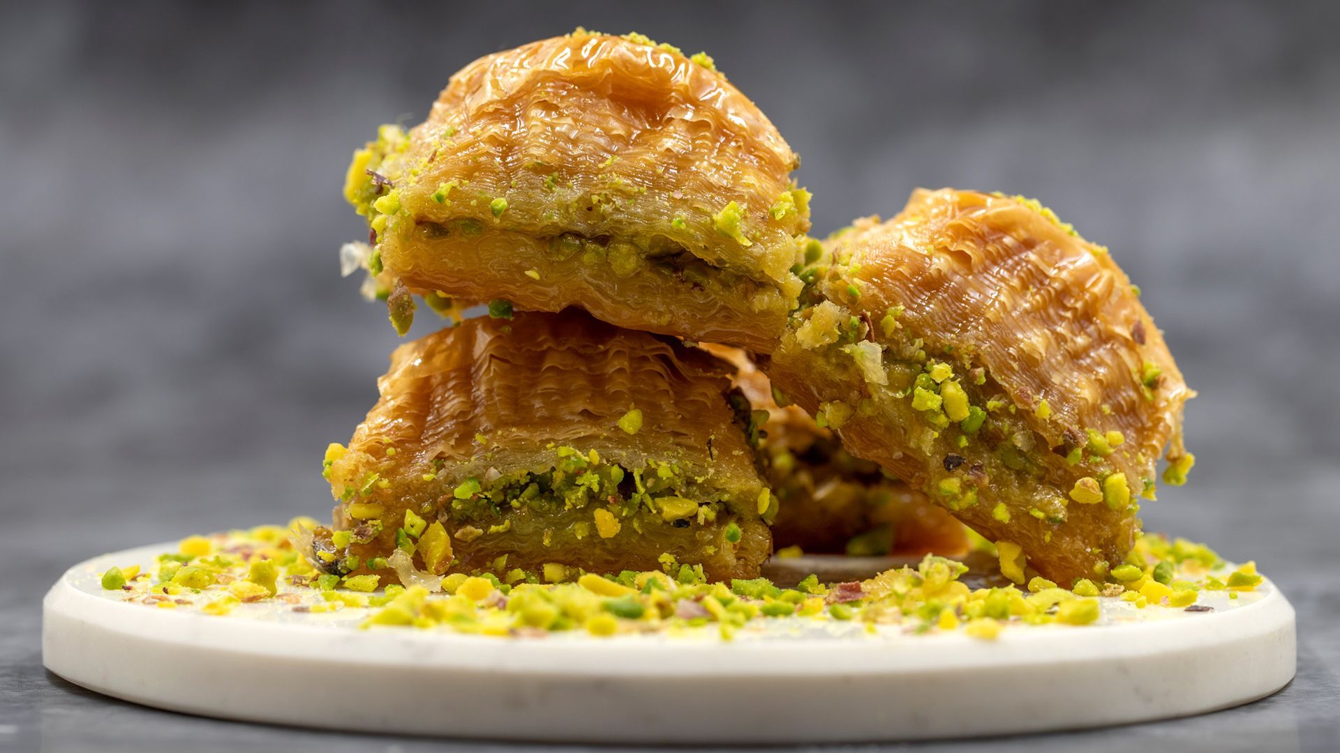 A stack of baklava with pistachios on a white plate