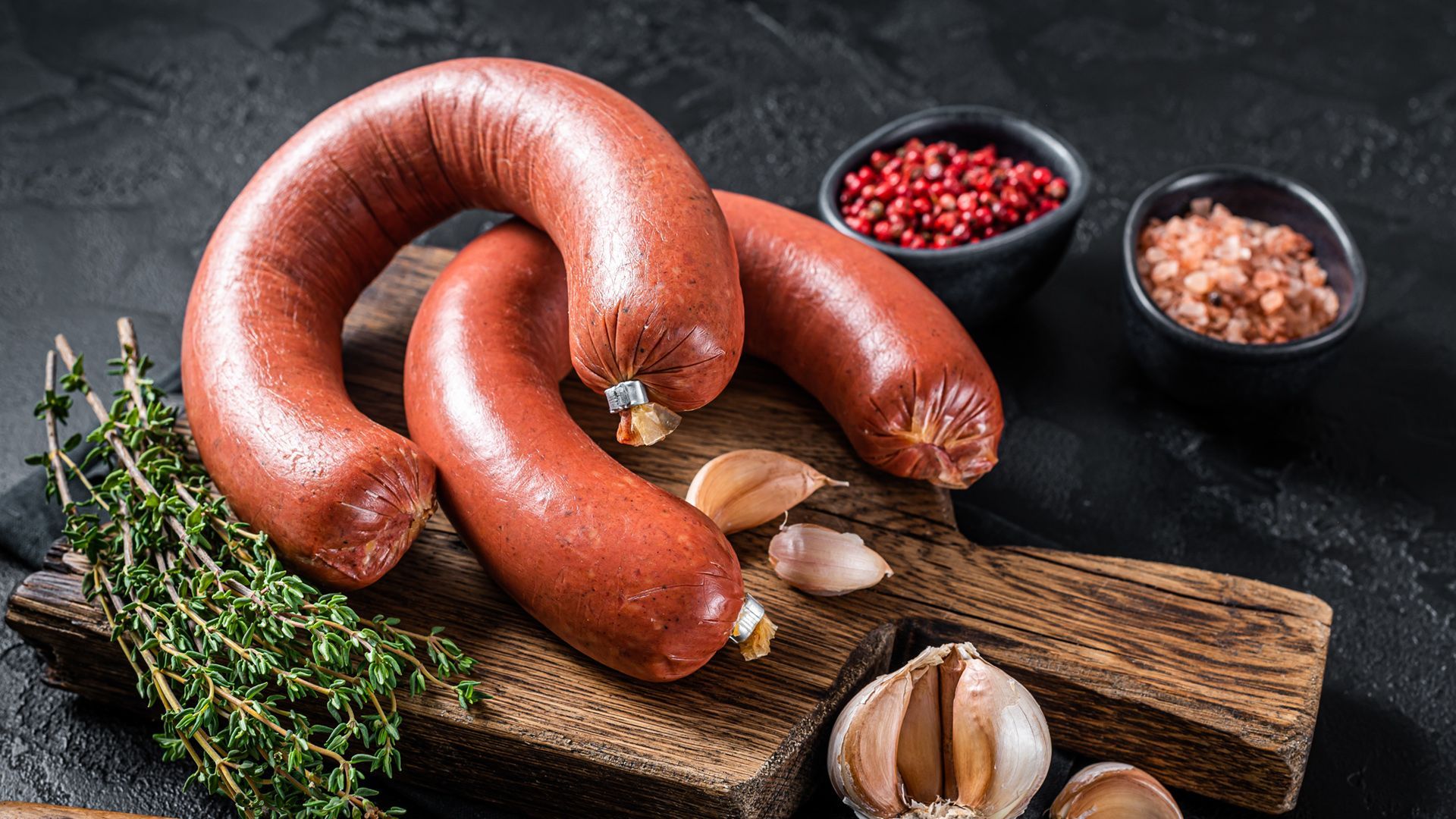 Two sausages are sitting on a wooden cutting board.