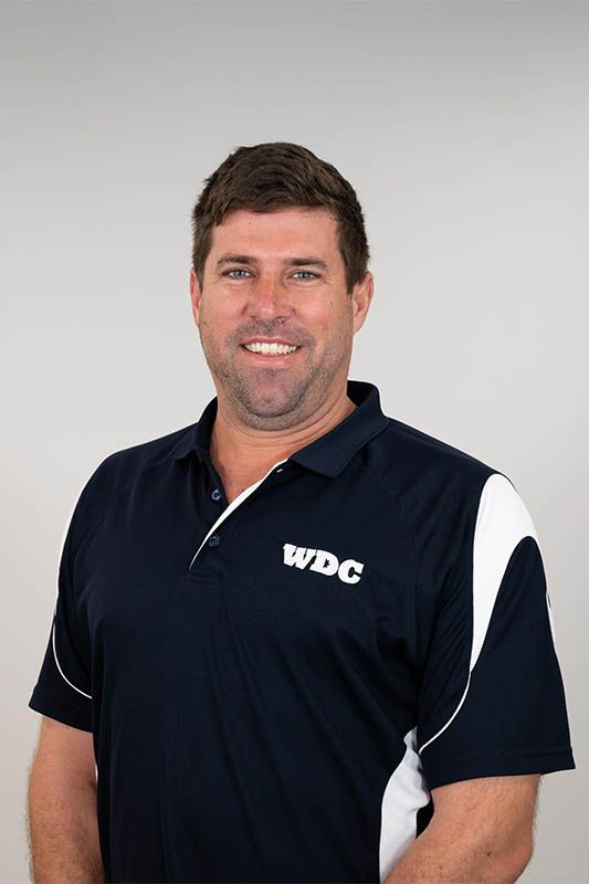 Man in a navy WBC polo shirt smiling against a light gray background