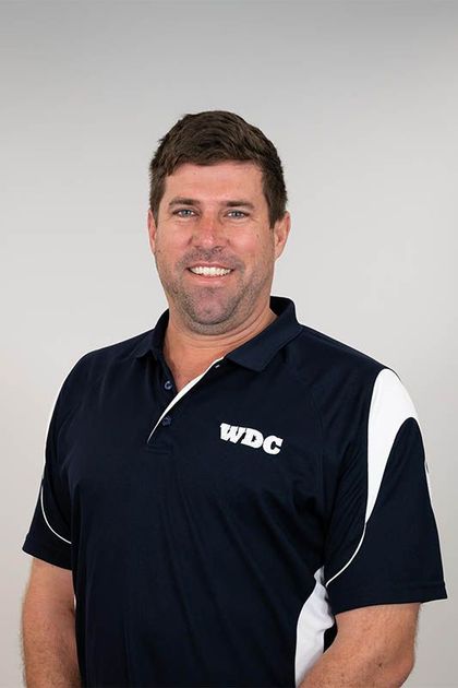 Man in a navy WBC polo shirt smiling against a light gray background