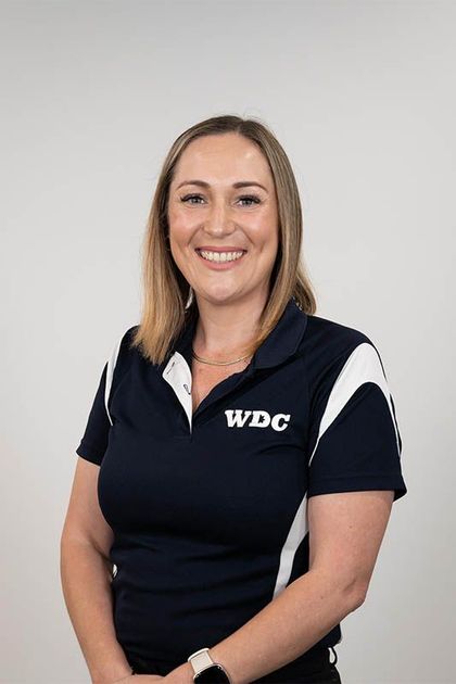 Woman in a navy WPC polo shirt smiling against a light gray background
