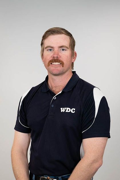 Man in a black WPC polo shirt standing against a light gray background