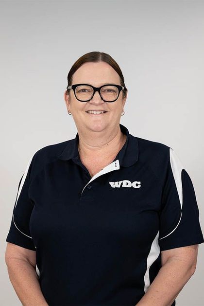 Smiling person in a navy WDC polo shirt against a light gray background