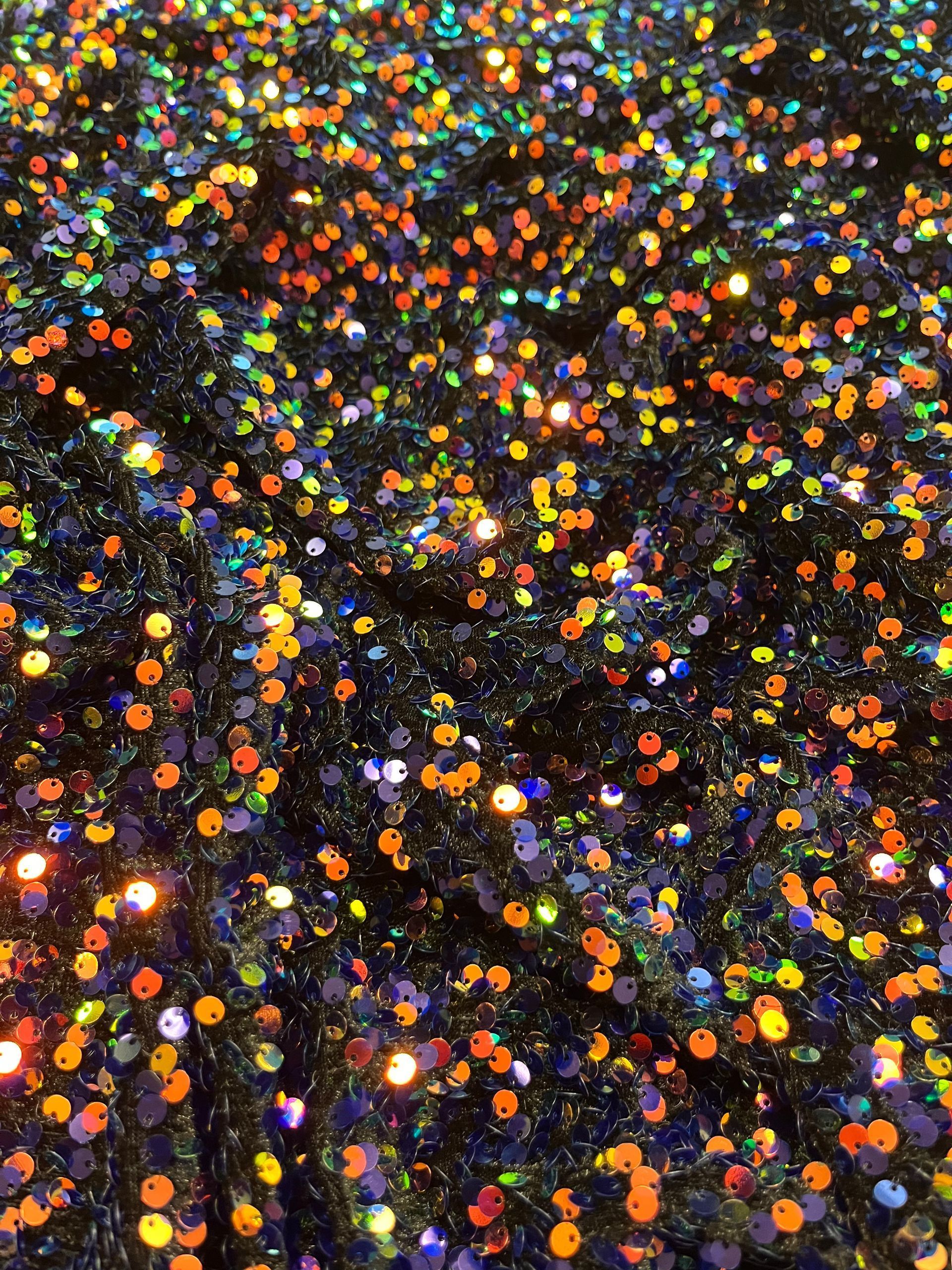 Primo piano di un mucchio di brillantini colorati su una superficie nera.