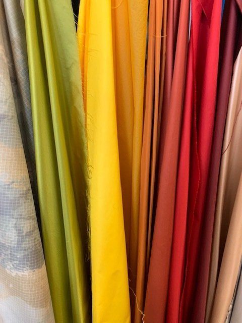 Un mucchio di tessuti di diversi colori sono appesi su uno scaffale.