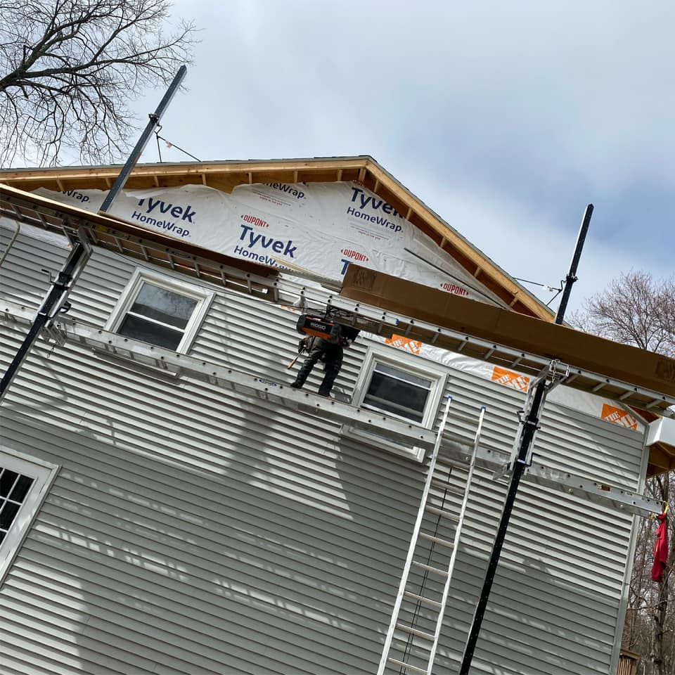 A man is standing on a ladder on the side of a house.