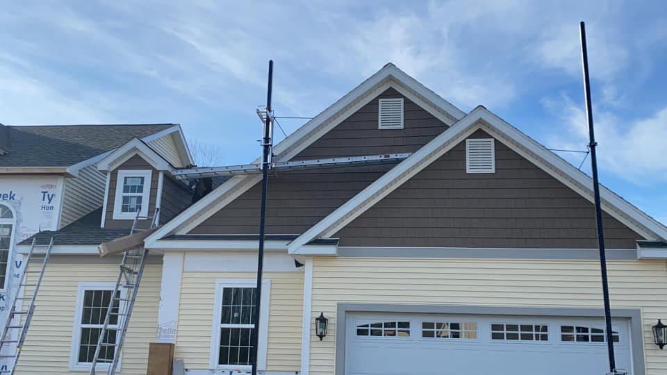 A yellow house with a white garage door is being built.