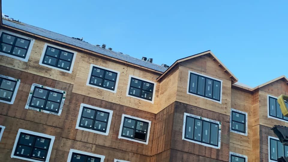 A large apartment building under construction with a blue sky in the background.