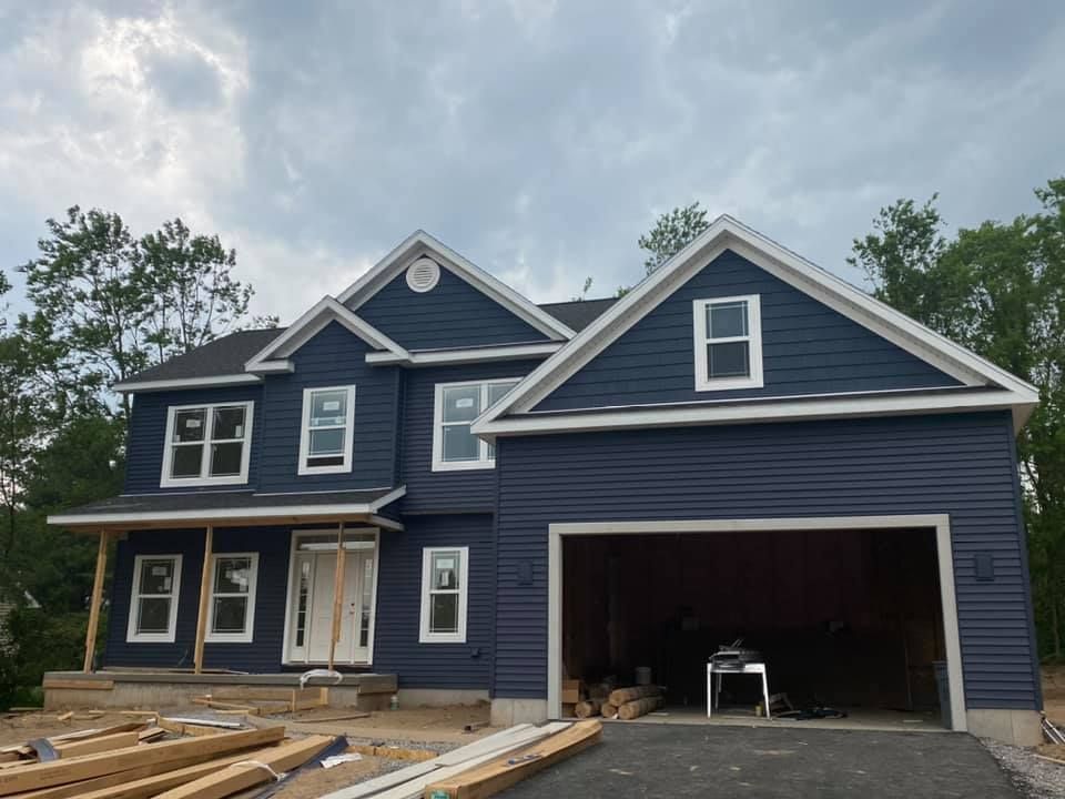 A large blue house with a garage under construction.