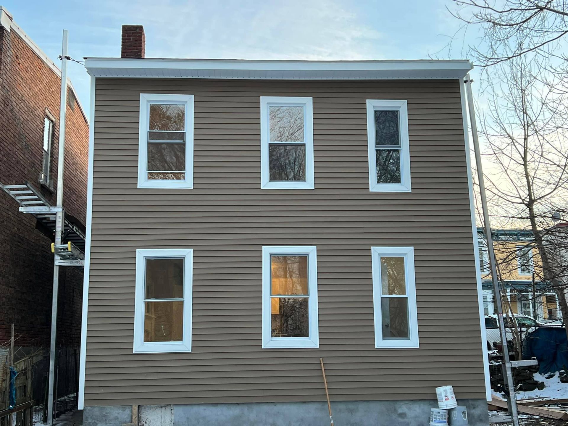 A brown house with white windows is under construction.