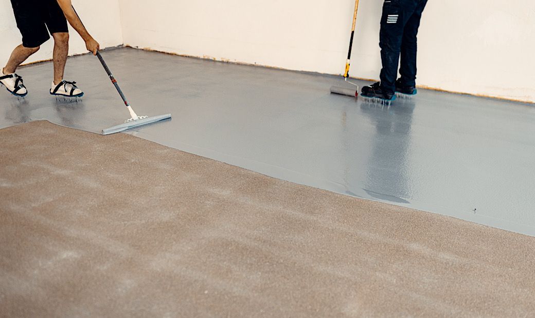 construction workers laying gloss coating on garage floor