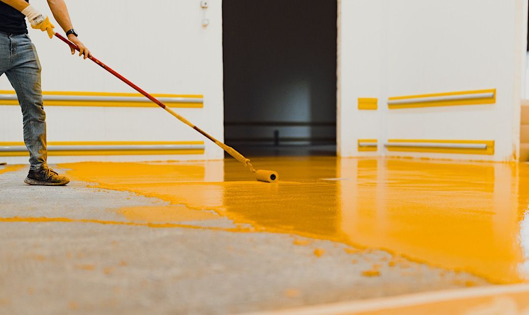 construction worker rolling polyurethane gloss on garage floor