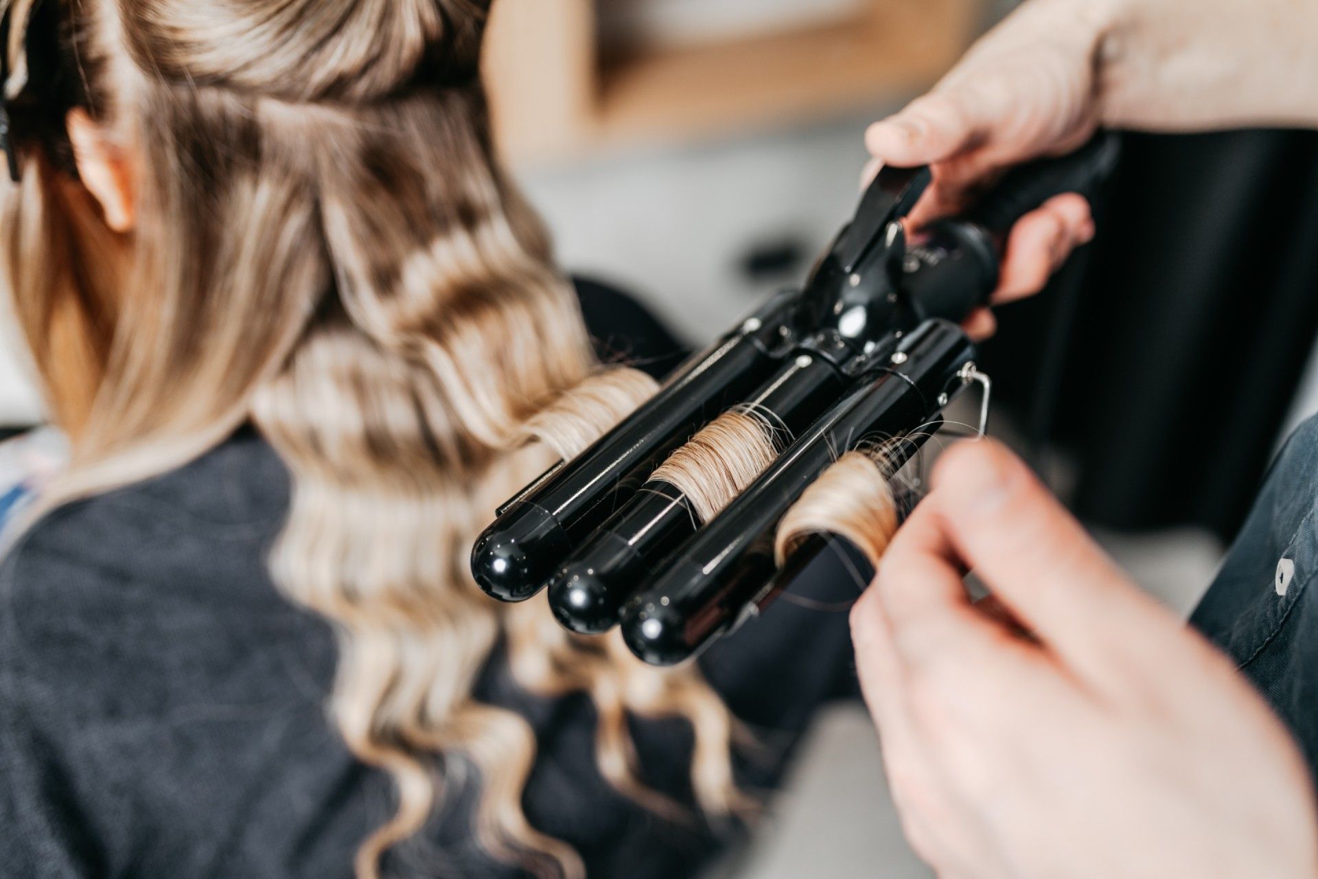 A woman is getting her hair curled by a hairdresser.