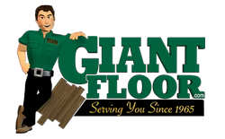 Giant Floor logo with a cartoon man leaning on wood planks and the slogan “Serving You Since 1965”