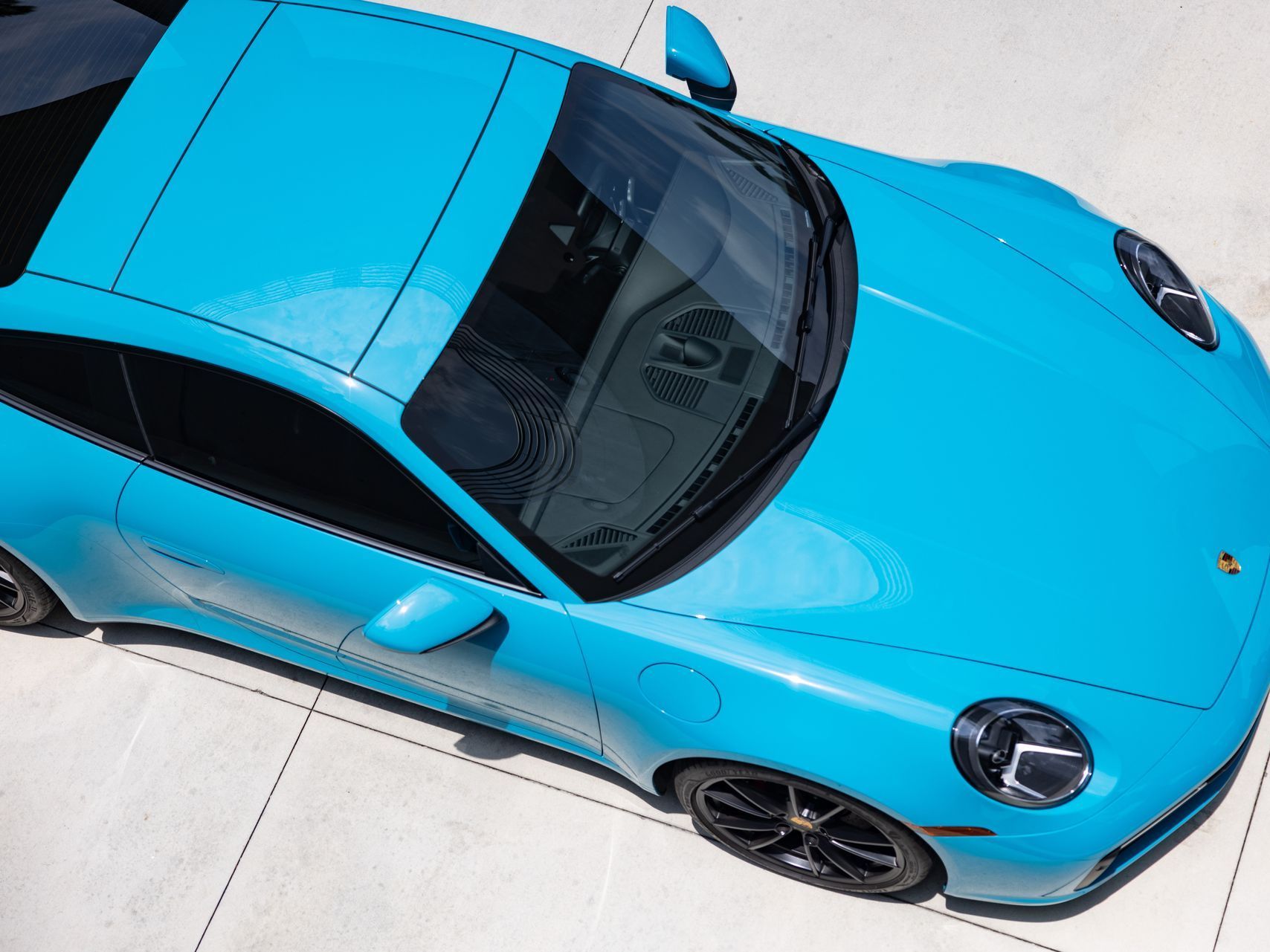 A blue porsche is parked on a concrete surface