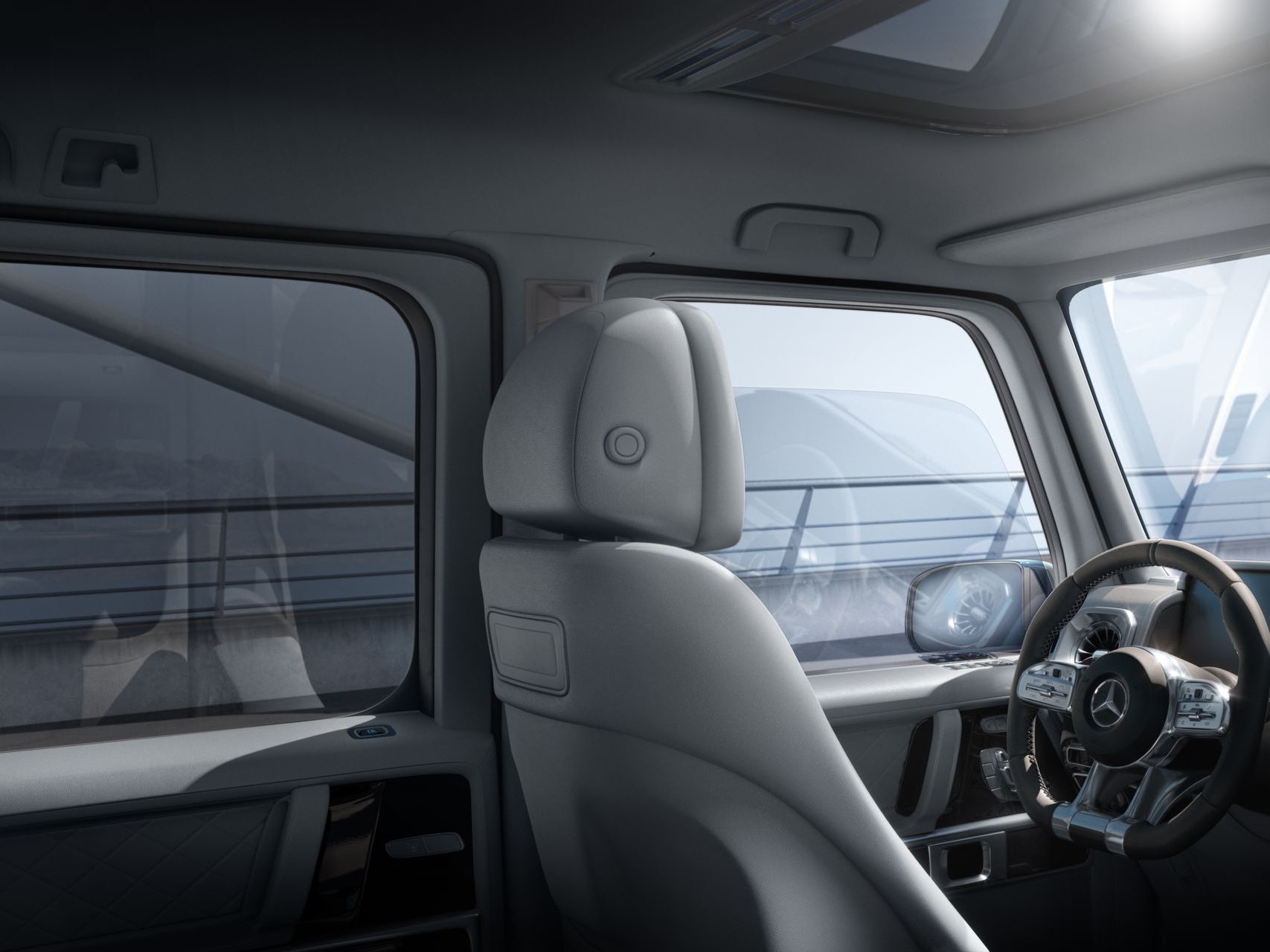 The inside of a car with a steering wheel and headrest