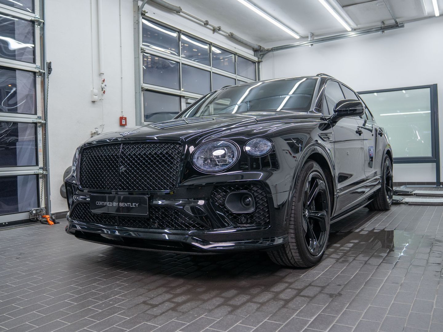 A black bentley bentayga is parked in a garage.