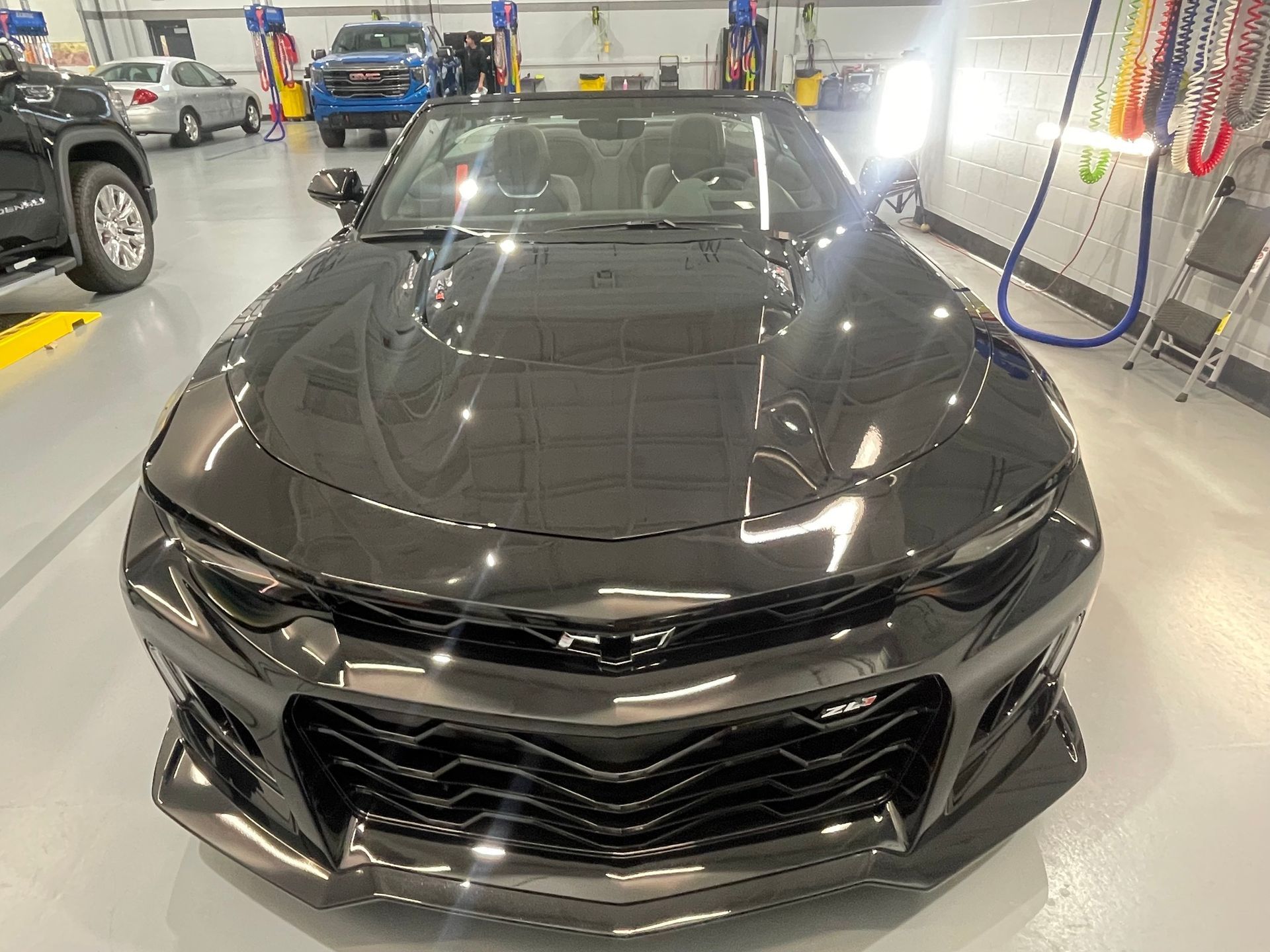 Black Chevrolet Camaro convertible in a garage.