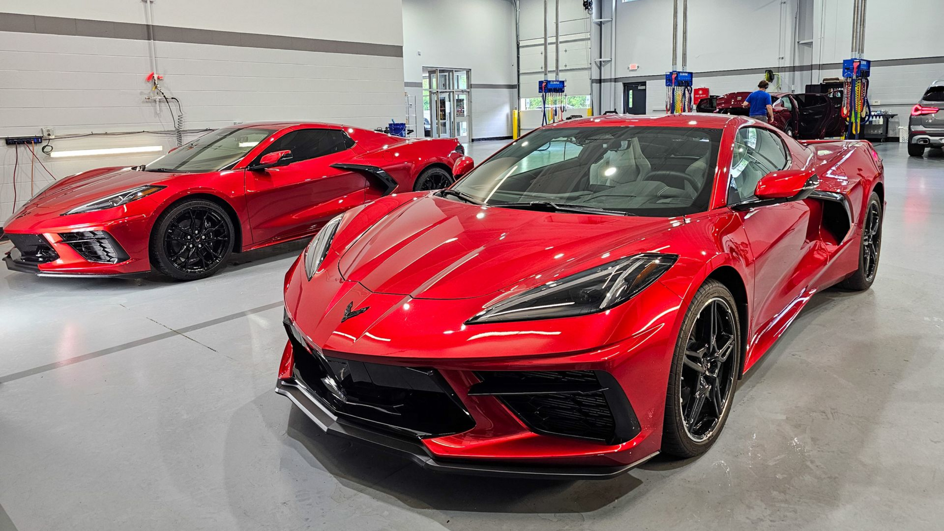 Two red Chevrolet Corvette sports cars in a garage.