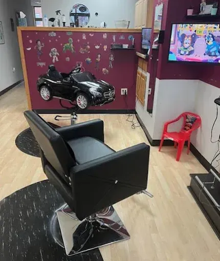 A barber shop with a chair and a toy car on the wall.