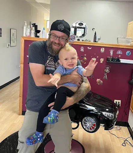 A man is holding a baby in his arms in a salon.