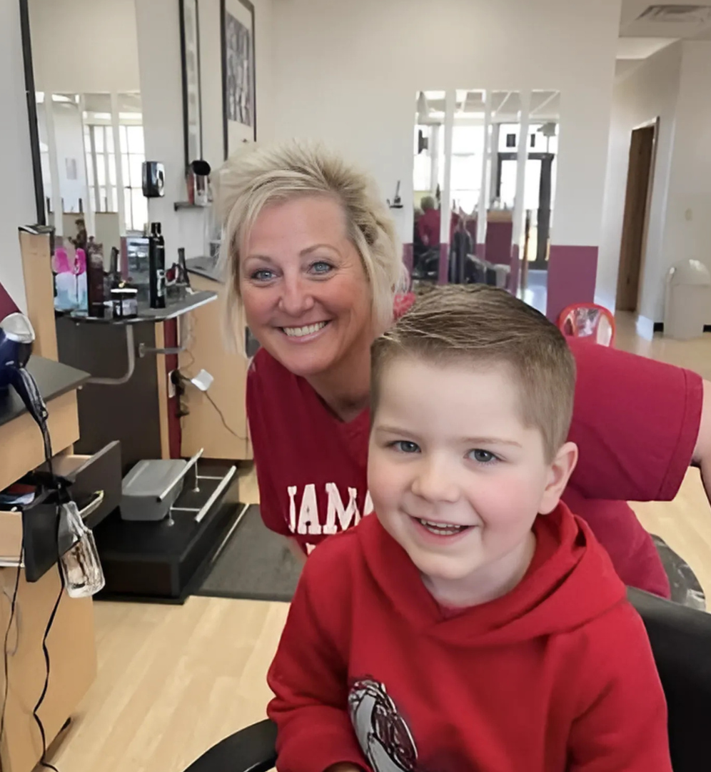 A woman in a red tam shirt sits next to a young boy