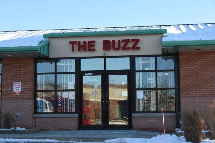 A brick building with a sign that says the buzz
